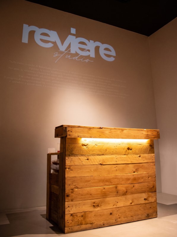 Il bancone in legno con il logo Reviere Studio proiettato sulla parete