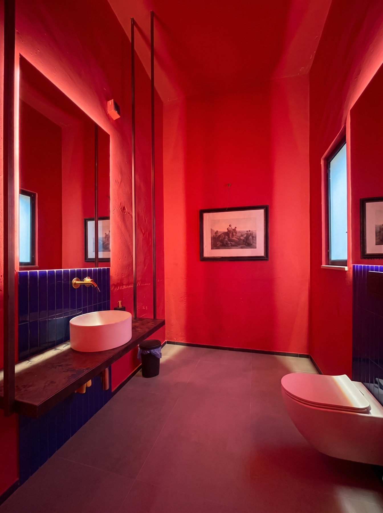 Bagno interno con pareti rosse, piastrelle blu e lavabo tondo