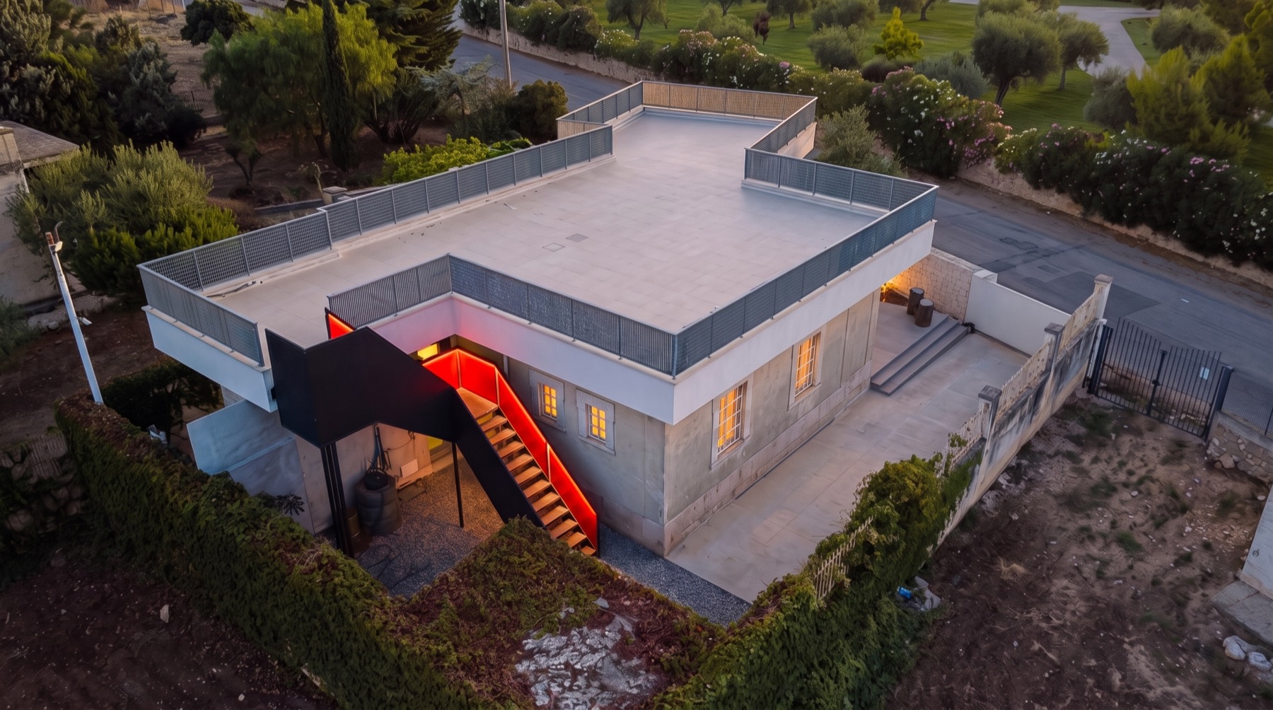 La struttura vista dal drone: tetto piano, scala esterna rossa e corte recintata