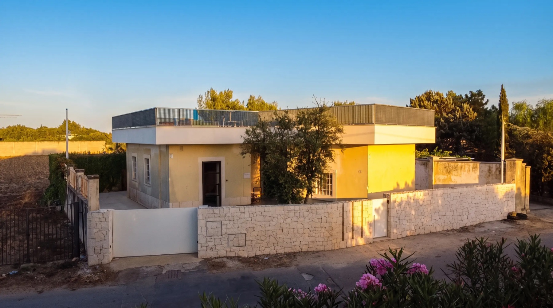 La villa e il muro di cinta in pietra visti frontalmente all&rsquo;ora dorata