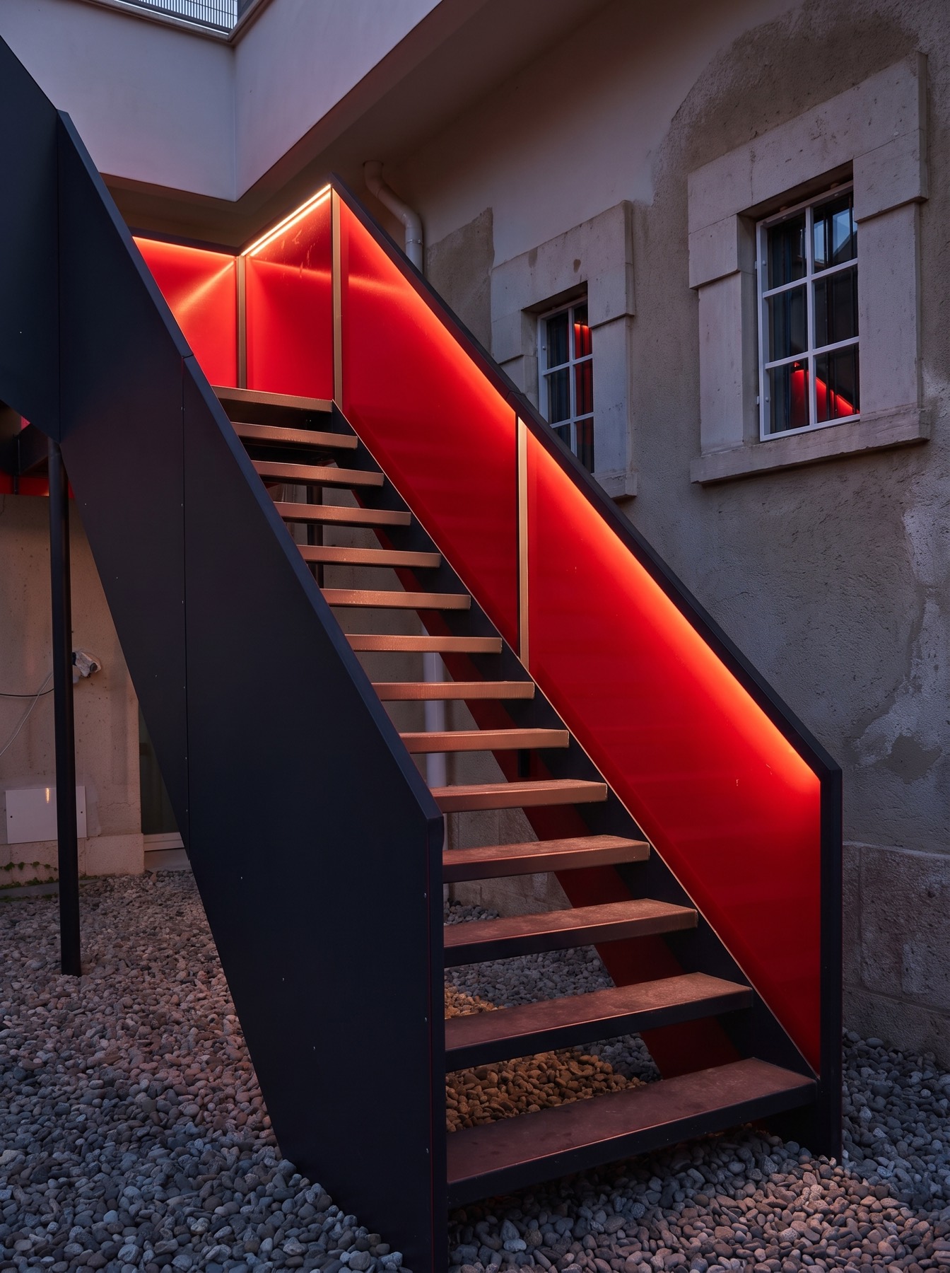 Scala esterna in legno e ferro con parete retroilluminata di rosso
